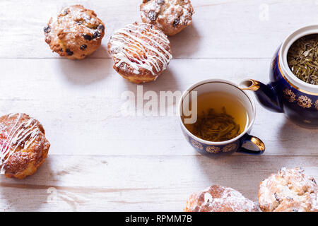 Tasses à thé, théière et muffins sur la table en bois blanc, Set théière et thé infusé avec des gâteaux sur la table, vert noir boisson chaude à base de plantes en pot en porcelaine, e Banque D'Images