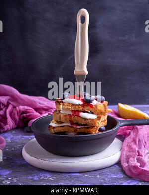 Pain perdu aux fruits rouges, sirop et la crème sure dans un noire fonte poêle, Close up Banque D'Images