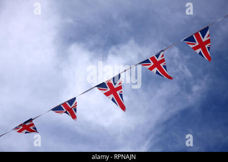 Drapeau britannique de l'Union Jack qui coute des drapeaux dans le ciel bleu célébrant la culture britannique Banque D'Images