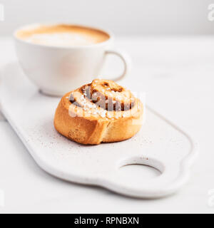 Petit-déjeuner suédois. À la cannelle fraîchement cuit avec des épices et du cacao du remplissage et du café ou du cappuccino blanc sur une assiette de plus de marbre blanc backgrou Banque D'Images