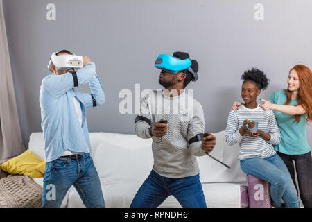 Des émotions young mixed race american bénéficiant d casque de réalité virtuelle, riant et gesticulant comme si l'interaction avec quelque chose. WOW moderne S Banque D'Images