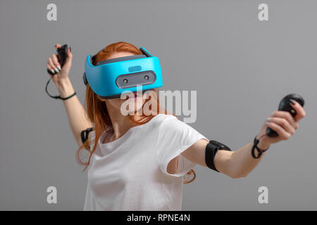 Jeune femme d'avoir du plaisir avec les nouvelles tendances de l'innovation technologie - concept de jeu - Isolé studio shot of rousse femme avec mobile bleu casque vr Futu Banque D'Images