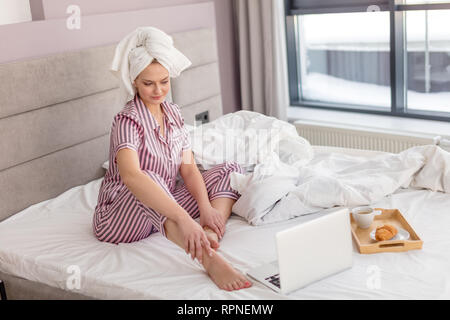 Belle femme en pyjama élégant à la recherche à l'écran de l'ordinateur. étudiant en ligne à la maison studing Banque D'Images