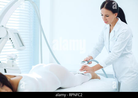 RF levée massage, Close up of cosmetologist médecin mains manipulant avec matériel cosmetological gadget. Ventre minceur et de l'abdomen. Slender Banque D'Images