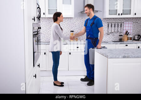 Vue latérale du jeune homme Plombier Shaking Hands With happy Woman Banque D'Images