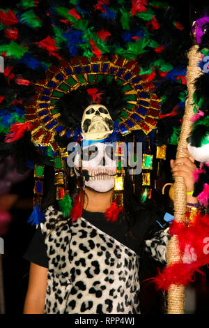 Jeune garçon déguisé, fortement colorés avec des plumes et du crâne, le port du masque maya leopard outfit, debout dans la rue au cours de l'assemblée annuelle cele mexicain Banque D'Images