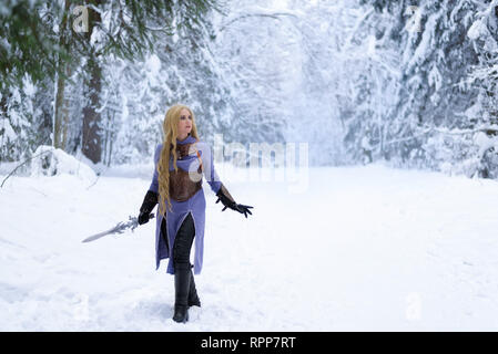 Warrior girl aux cheveux blonds et aux gros ax en forêt d'hiver Banque D'Images