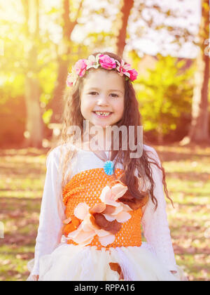 Petite fille dans le jardin contre le soleil en tutu robe et bandeau à fleurs, tonique, selective focus Banque D'Images