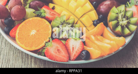 Les bleuets, fraises fruits assortis, mangue, orange, pamplemousse papaye bananes, raisins, kiwis apple sur le fond en bois gris, tonique, bannière photo, selective focus Banque D'Images