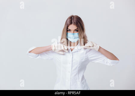 Portrait de femme médecin avec masque de visage prend off white gants médicaux Banque D'Images