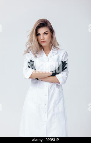 Portrait of young female professional cosmetologist en gants noirs. Femme médecin coiffeur en studio
