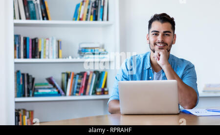 Penser l'homme hipster mexicain travaillant avec l'ordinateur au bureau à la maison Banque D'Images