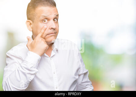 L'âge moyen homme élégant arabes sur fond isolé pointant à l'oeil vous regarde le geste, expression suspecte Banque D'Images