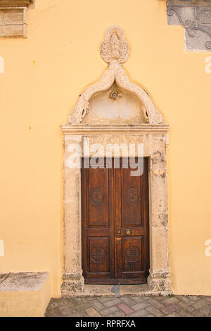 La façade jaune, porte en bois décoré, entrée à l'église orthodoxe. Antique décorative en pierre, portail de porte avec des reliefs et de petits tympan. Banque D'Images