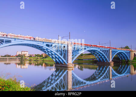 Train de fret transportant voitures sur Blue steel pont ferroviaire sur la rivière Drawa. Train de marchandises, le transport ferroviaire. Reflets dans l'eau. Maribor, Slovénie. Banque D'Images