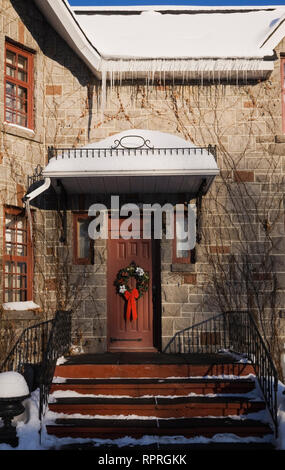 Vue partielle d'une maison de deux étages en hiver avec porte avant ornée d'une couronne de Noël Banque D'Images