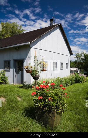 Ancienne grange en bois peint blanc 1913 et jardin fleuri dans un jardin résidentiel Banque D'Images