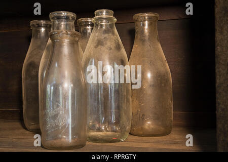 Close-up de quelques vieilles bouteilles de lait à l'intérieur d'un meuble ancien dans la cuisine d'une vieille maison de style cottage Canadiana 1826 Banque D'Images