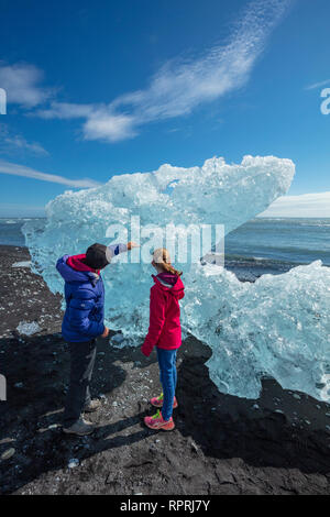 Personnes examinant les icebergs sur Breidamerkursandur plage de sable noir, sous Jokulsarlon. Sudhurland, au sud est de l'Islande. Banque D'Images