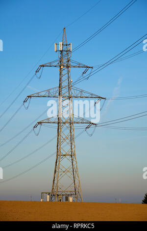 Un pylône à haute tension avec les antennes GSM ou 4G contre un ciel bleu à la campagne Banque D'Images