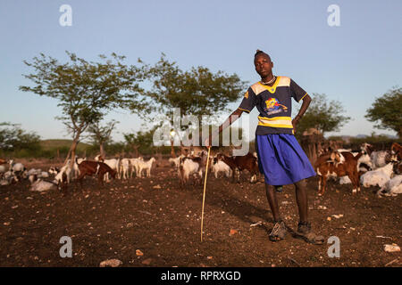 Garçon à la recherche après l'Himba chèvres dans un village près d'Epupa Falls, Kunene, Namibie, Afrique du Sud Banque D'Images