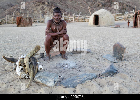 Le chef du village Himba assis par cheminée, Purros, Namibie Banque D'Images