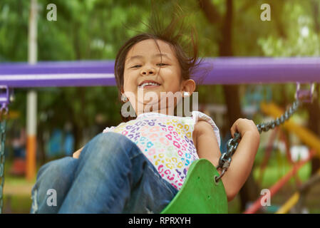 Happy asian girl sur balançoires accrocher sur high point Banque D'Images