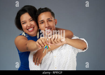 Jeune couple excité avec clé de la maison sur l'arrière-plan gris studio Banque D'Images