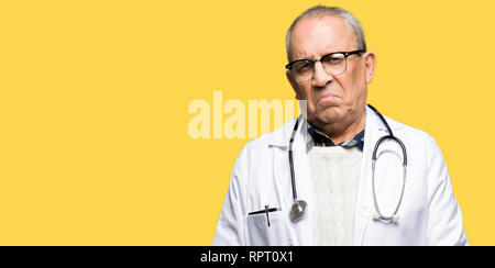 Beau médecin senior homme portant un manteau médicale appuyée et l'inquiétude de la détresse, de pleurer en colère et peur. Expression triste. Banque D'Images