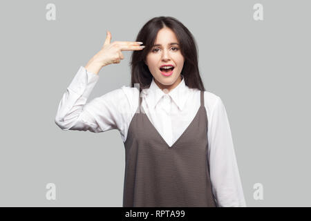 Portrait de fou belle jeune femme en chemise blanche et tablier brun avec le maquillage et les cheveux brune et à la recherche à l'appareil photo avec fusil pistolet ge Banque D'Images