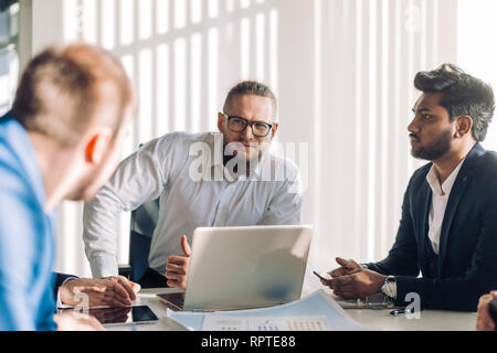 Homme d'optimiste confiant en chemise bleu pâle et son équipe. Caucasian business executive barbu avec dossier. Les employés de bureau concept Banque D'Images