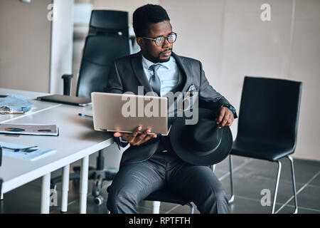 Jeune élégante pensive african american businessman using laptop. la photo en gros. technologie . Temps libre Banque D'Images