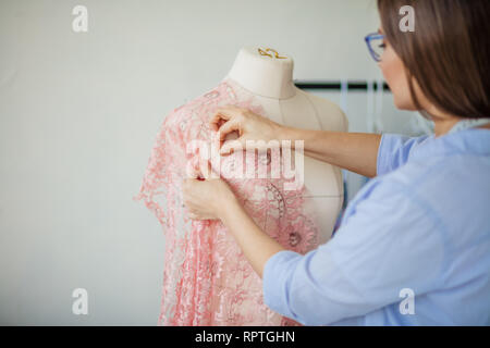 Créateur de mode habile couturière se trouve dans un studio près de le mannequin et correctifs dentelle, à l'aide d'aiguilles. Création ou la modélisation de la mode Banque D'Images