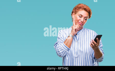 Atrractive young redhead woman texting en utilisant blackberry sur fond isolé visage sérieux de penser à question, idée très confus Banque D'Images