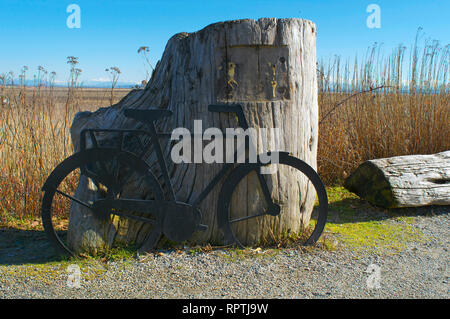 Réplique d'un vélo appuyé contre une souche trouvée le long de la digue de Boundary Bay Trail à Tsawwassen, en Colombie-Britannique, Canada. Banque D'Images