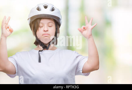 Les jeunes cyclistes adultes femme avec le syndrome de porter un casque de sécurité sur fond isolé se détendre et sourire avec les yeux fermé faisant la méditation gestur Banque D'Images