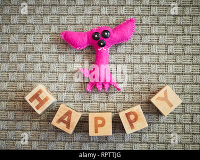 Jouet en bois faits main et chien alphabet blocks spelling heureux sur moquette grise. Jouets éducatifs pour les enfants en école maternelle. Banque D'Images