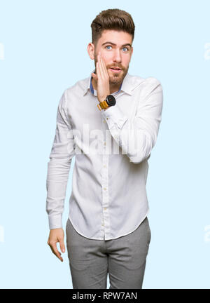Beau jeune homme d'affaires main sur bouche secret disant rumeur, chuchotant amorce une conversation malveillant Banque D'Images