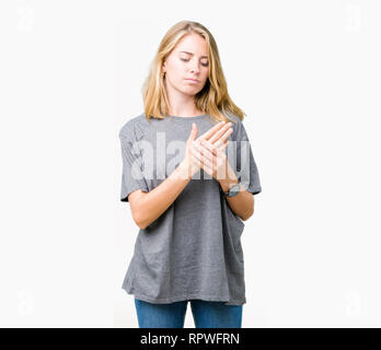 Belle jeune femme portant des T-shirt oversize sur fond isolés souffrant de douleur sur les mains et les doigts, l'inflammation de l'arthrite Banque D'Images