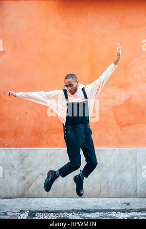 Jeune homme noir portant des vêtements décontractés jumping outdoors Banque D'Images