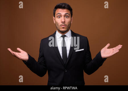 Beau jeune homme d'origine hispanique contre fond brun Banque D'Images