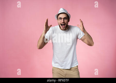 Surpris, l'homme heureux expressif isolé sur rose. Banque D'Images