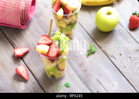 Sport et mode de vie sain Concept. Tapis de yoga rose et salade de fruits et baies en tasse en plastique pour accéder, copier l'espace, vue d'en haut. Banque D'Images