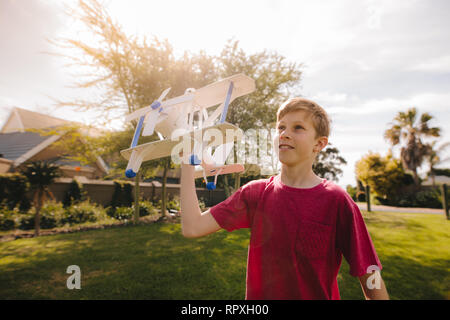 Garçon s'amusant à jouer avec la couleur blanc plan jouet en plein air. Enfant jouant avec un jouet avion sur une journée ensoleillée. Banque D'Images