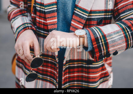 Close-up détails de l'accessoire de mode, élégante jeune femme portant un manteau avec un motif tartan, un anneau d'or, une paire de lunettes de soleil et moderne Banque D'Images