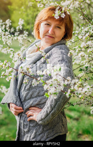 Femme d'âge moyen des promenades dans le jardin de printemps parmi les arbres en fleurs. Concept de la fête des Mères Banque D'Images