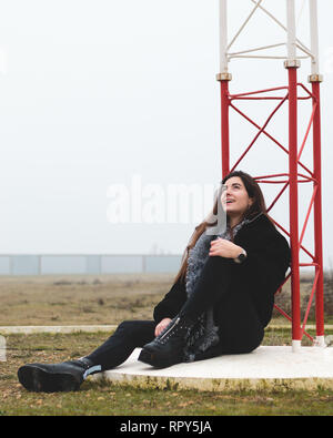 Belle Jeune femme assise sur le sol dans un petit aéroport à dans un petit aéroport dans un paysage rural. Jolie femme en riant et smili Banque D'Images