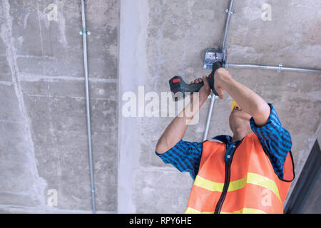 Travailleur de la construction de la vis et de mettre en place dans la construction électrique Banque D'Images