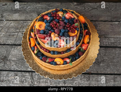 Gâteau au fromage avec fruits et de baies sur la vieille bandes, du sucre en poudre Banque D'Images