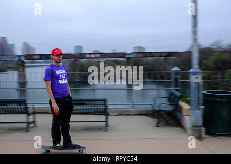 Homme avec MAGA hat et construire le mur en T-Shirt skateboard électrique à Austin, TX, USA Banque D'Images